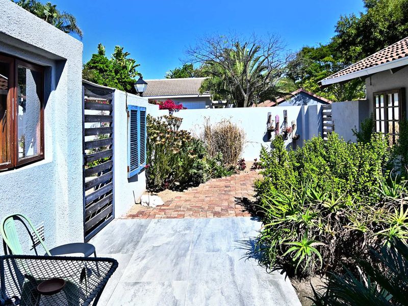 A private rear courtyard featuring a combination of tiled patio and brick paving, enclosed by boundary walls with established garden landscaping.