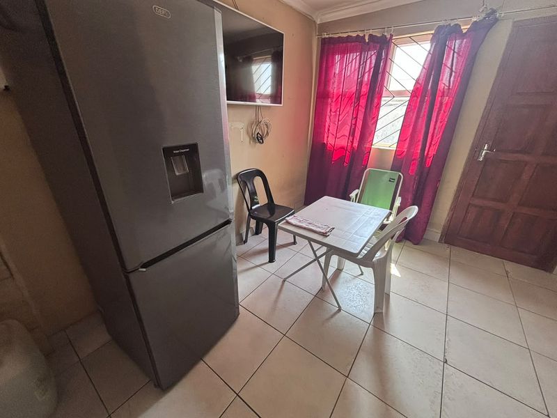 A functional kitchen area featuring tiled flooring and a window with security bars, offering a practical space for daily use.