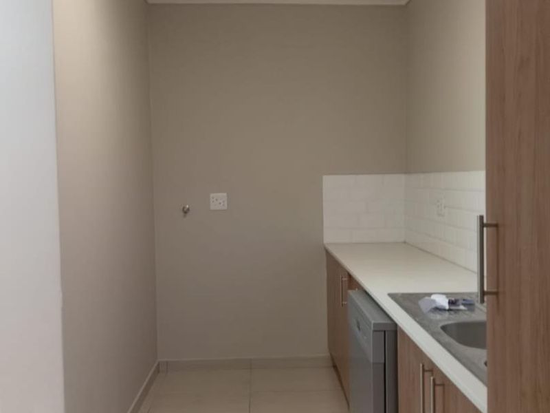 A clean and functional laundry area featuring built-in cabinetry, a stainless steel sink, and a subway tile backsplash.