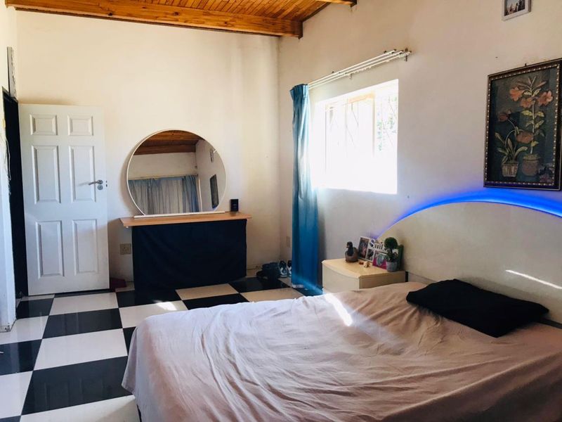 A bedroom featuring exposed timber ceiling beams and distinctive black and white checkered floor tiles, offering a unique aesthetic foundation.