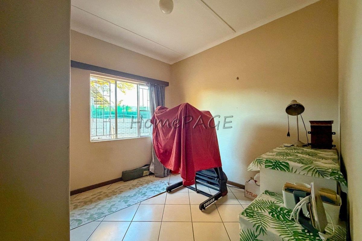 A bedroom featuring tiled flooring and a window with security bars, offering a functional space ready for personalization.