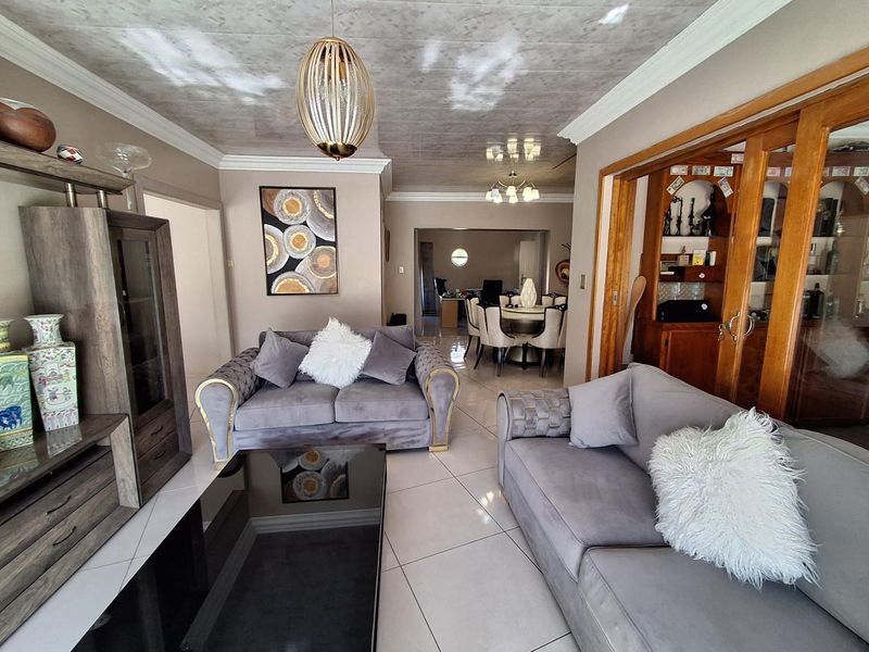 Spacious open-plan living area featuring polished tile flooring, decorative crown molding, and sliding wooden doors connecting to the adjacent dining space.