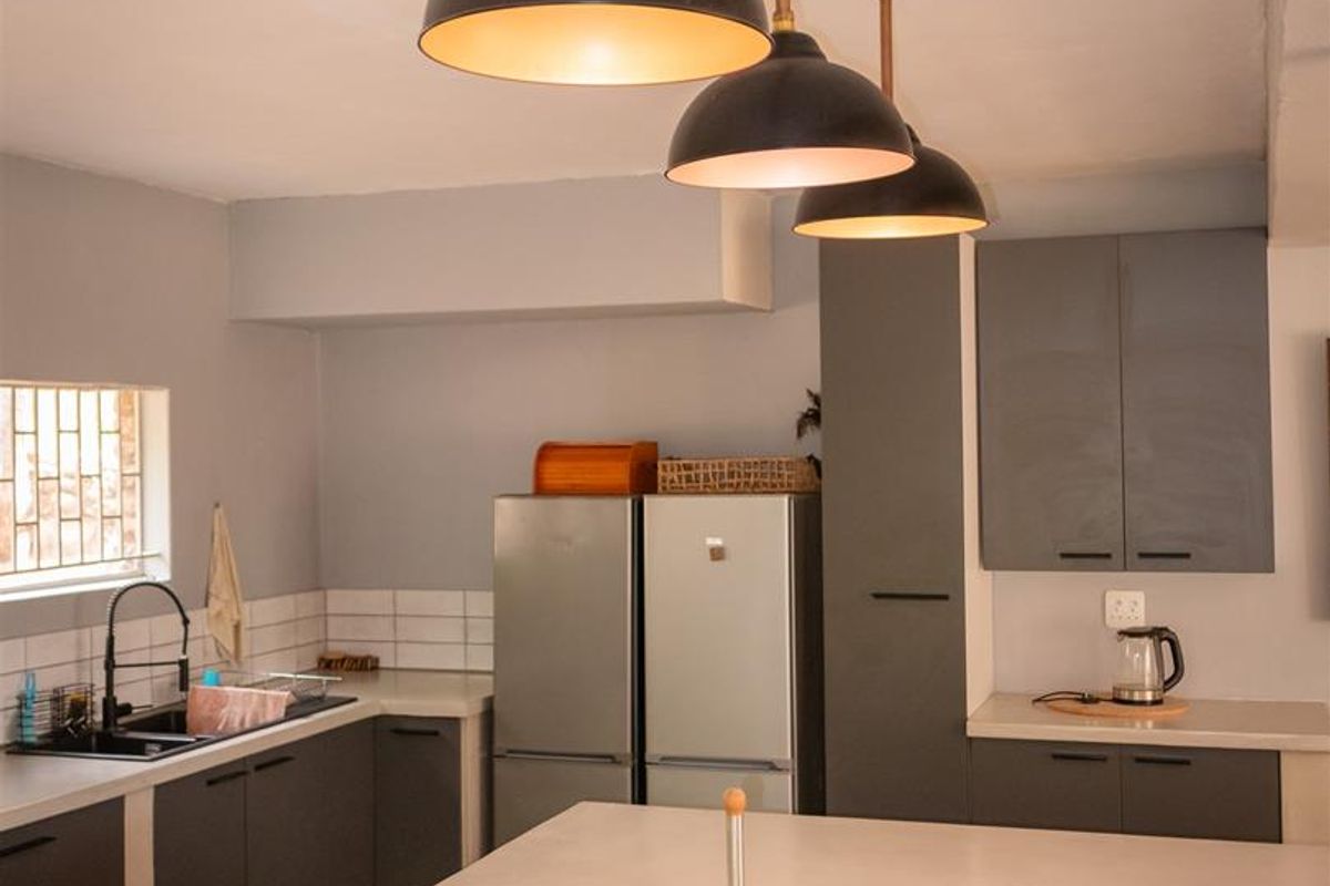 Modern kitchen featuring a central island, dark grey cabinetry, subway tile backsplash, and industrial-style pendant lighting.