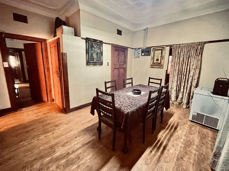 A traditional dining room featuring timber door frames, ornate ceiling cornices, and wood-look flooring, offering a classic layout with multiple access points.