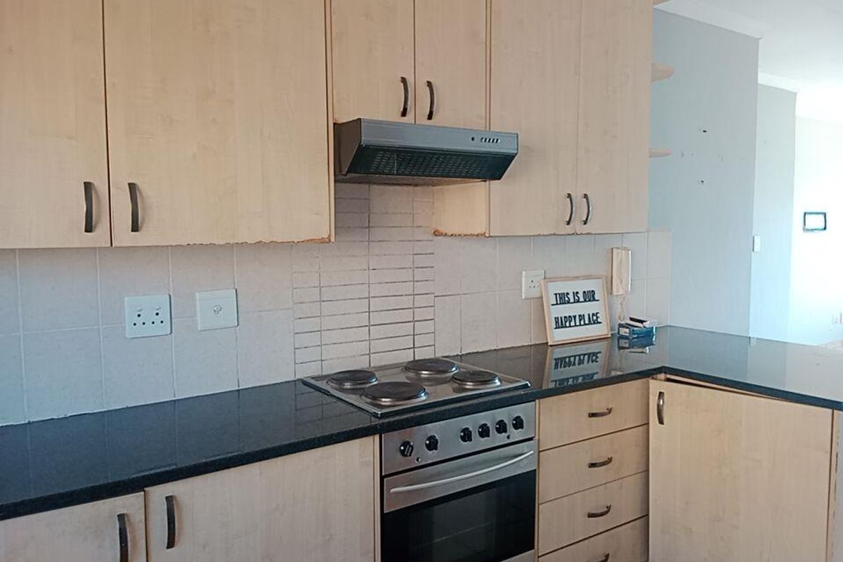 A functional kitchen featuring light wood-tone cabinetry, dark granite countertops, a built-in electric oven, and a tiled backsplash.