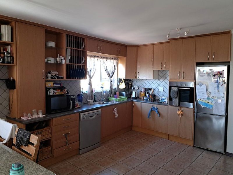 A functional kitchen featuring wood-look laminate cabinetry, a built-in oven, tiled backsplash, and ceramic floor tiles, offering a classic layout with ample storage.