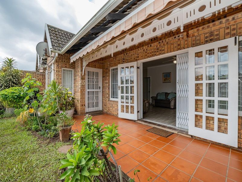 A covered brick patio with terracotta tiling, featuring decorative timber trim and french doors providing access to the interior living space.