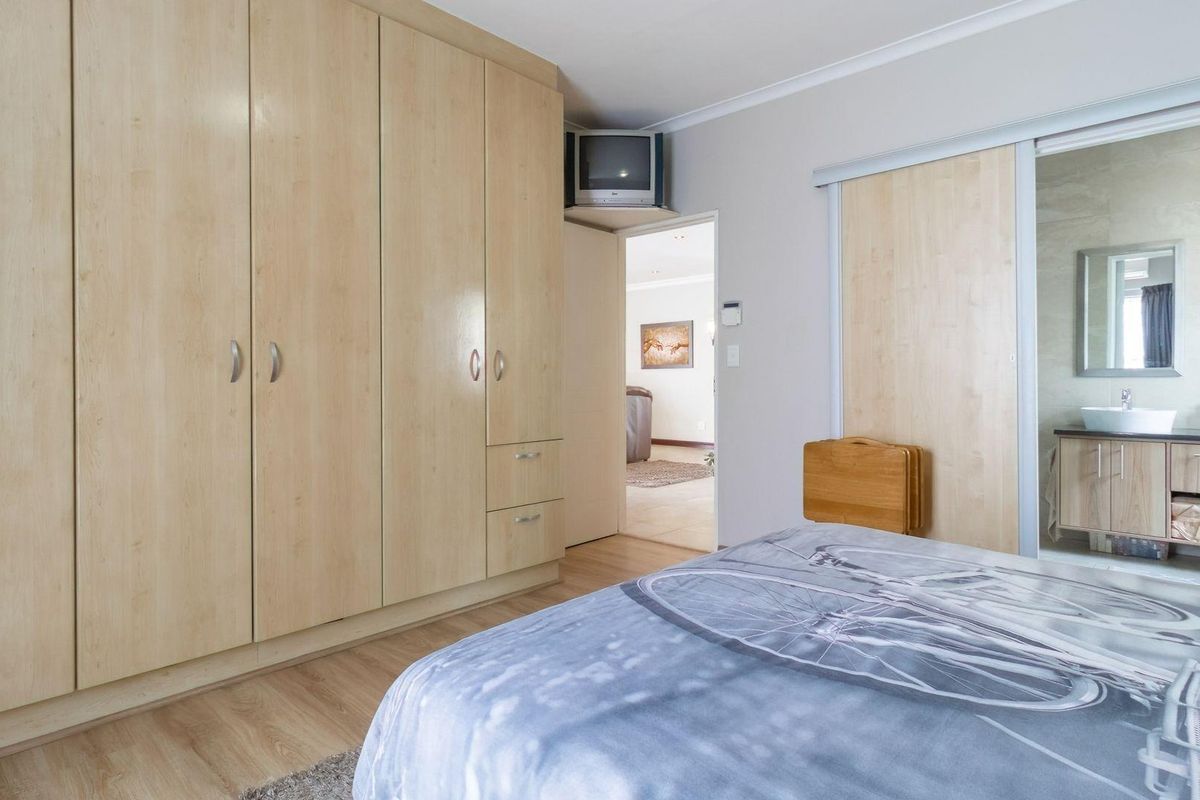 Bedroom featuring built-in light wood cabinetry and an en-suite bathroom with a vanity and basin, accessible via a sliding door.