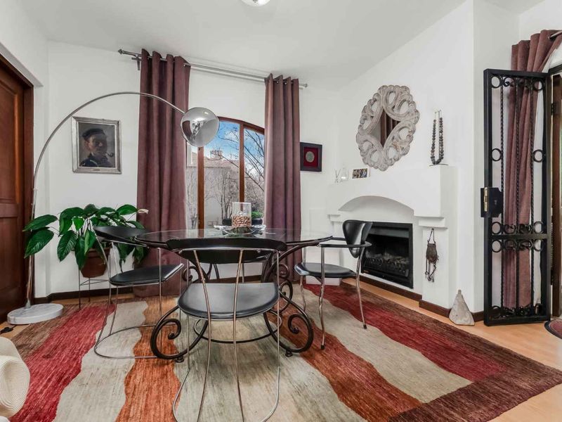 A dining room featuring a built-in fireplace, arched window, and security gate, finished with laminate flooring.