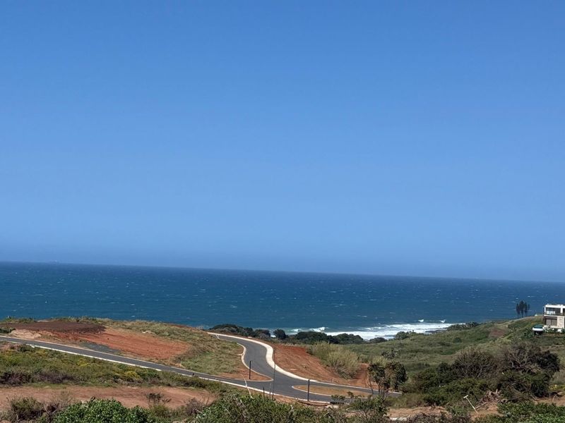 A scenic view of the coastline and ocean from the vacant residential land, featuring paved road access and surrounding natural landscape.