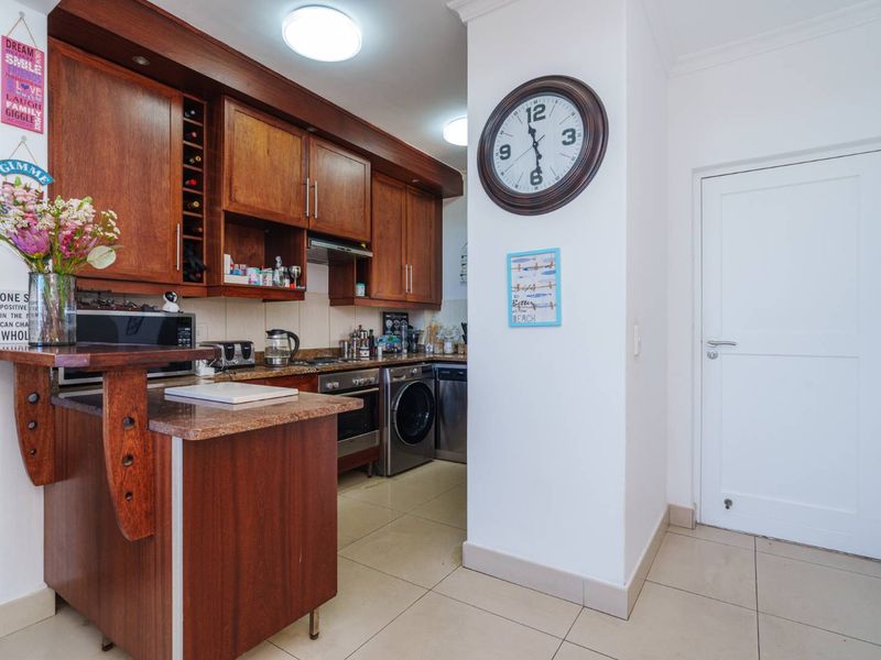 A functional kitchen featuring warm-toned wooden cabinetry, granite countertops, and integrated appliances, providing a practical workspace with tiled flooring.