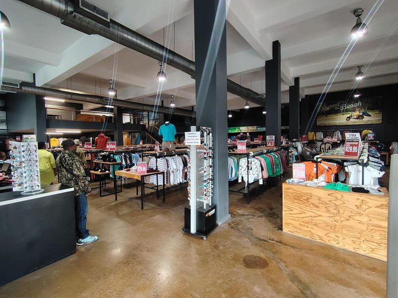 Spacious retail floor featuring industrial-style exposed ducting, polished concrete flooring, and a mezzanine level, providing an open-plan layout suitable for various commercial uses.