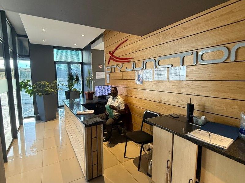 Modern apartment building reception area featuring a professional desk, built-in cabinetry, and sleek tiled flooring with glass partitions.