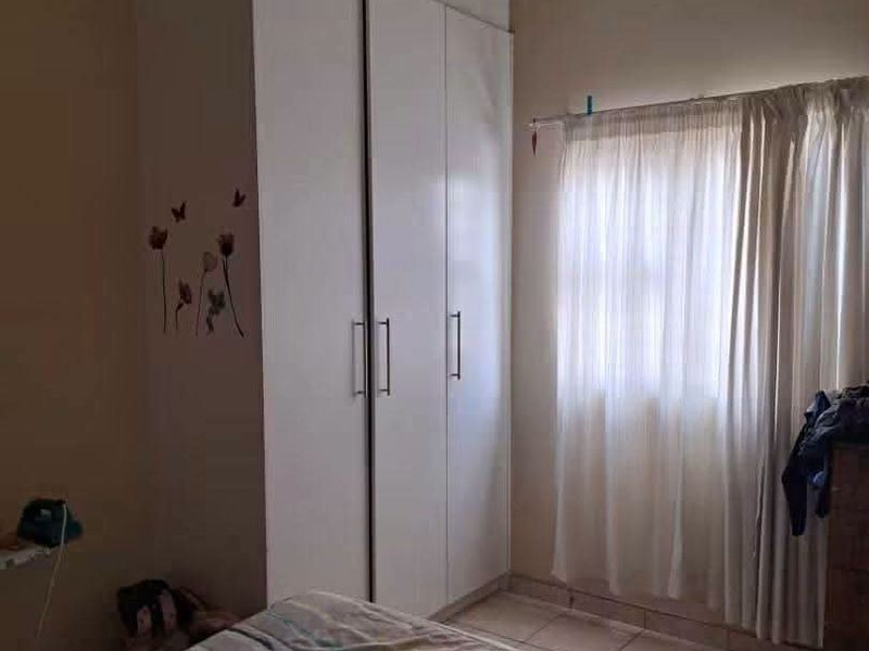 A bedroom featuring a built-in wardrobe, tiled flooring, and a drop ceiling, providing a functional and practical living space.