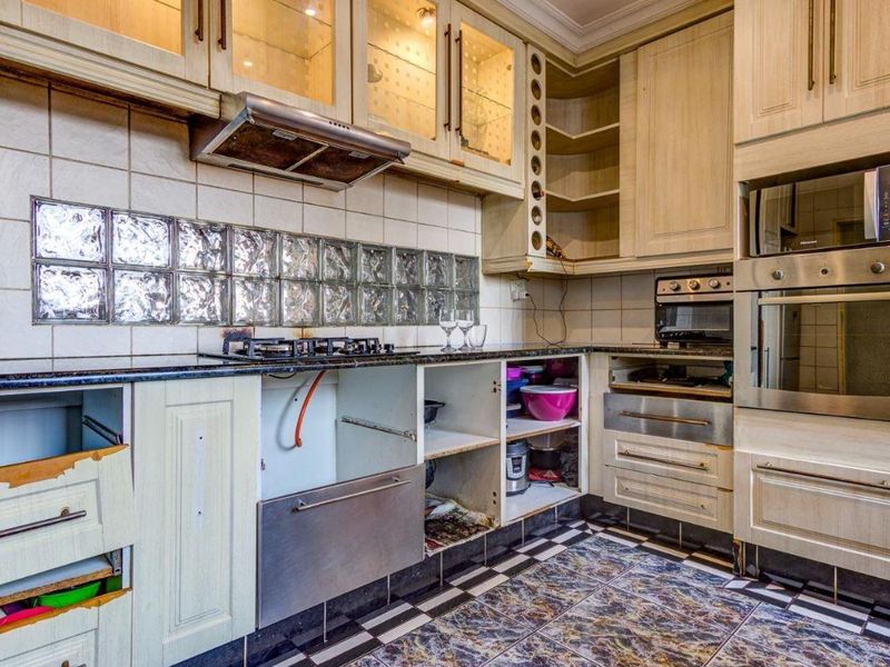 A dated kitchen featuring built-in cabinetry, gas hob, and integrated appliances, currently requiring maintenance and cosmetic updates to restore its functionality and aesthetic appeal.