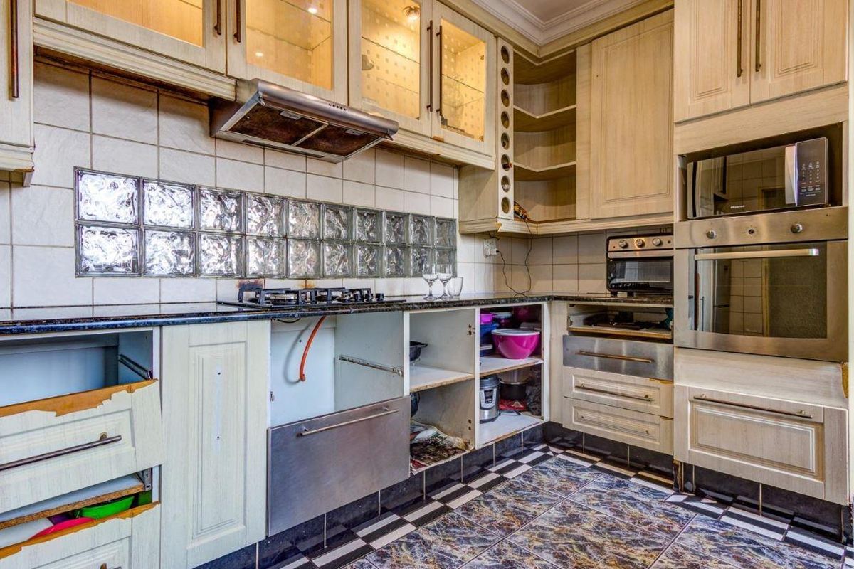 A dated kitchen featuring built-in cabinetry, gas hob, and integrated appliances, currently requiring maintenance and cosmetic updates to restore its functionality and aesthetic appeal.