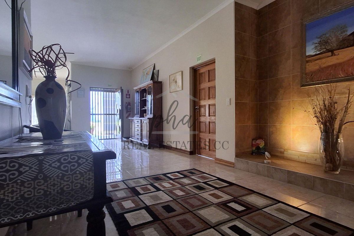 Spacious living area featuring tiled flooring and a prominent built-in fireplace with decorative tiling, leading towards an exterior entrance.