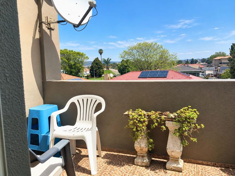 A private balcony featuring tiled flooring and a parapet wall, offering an elevated view of the surrounding neighborhood.