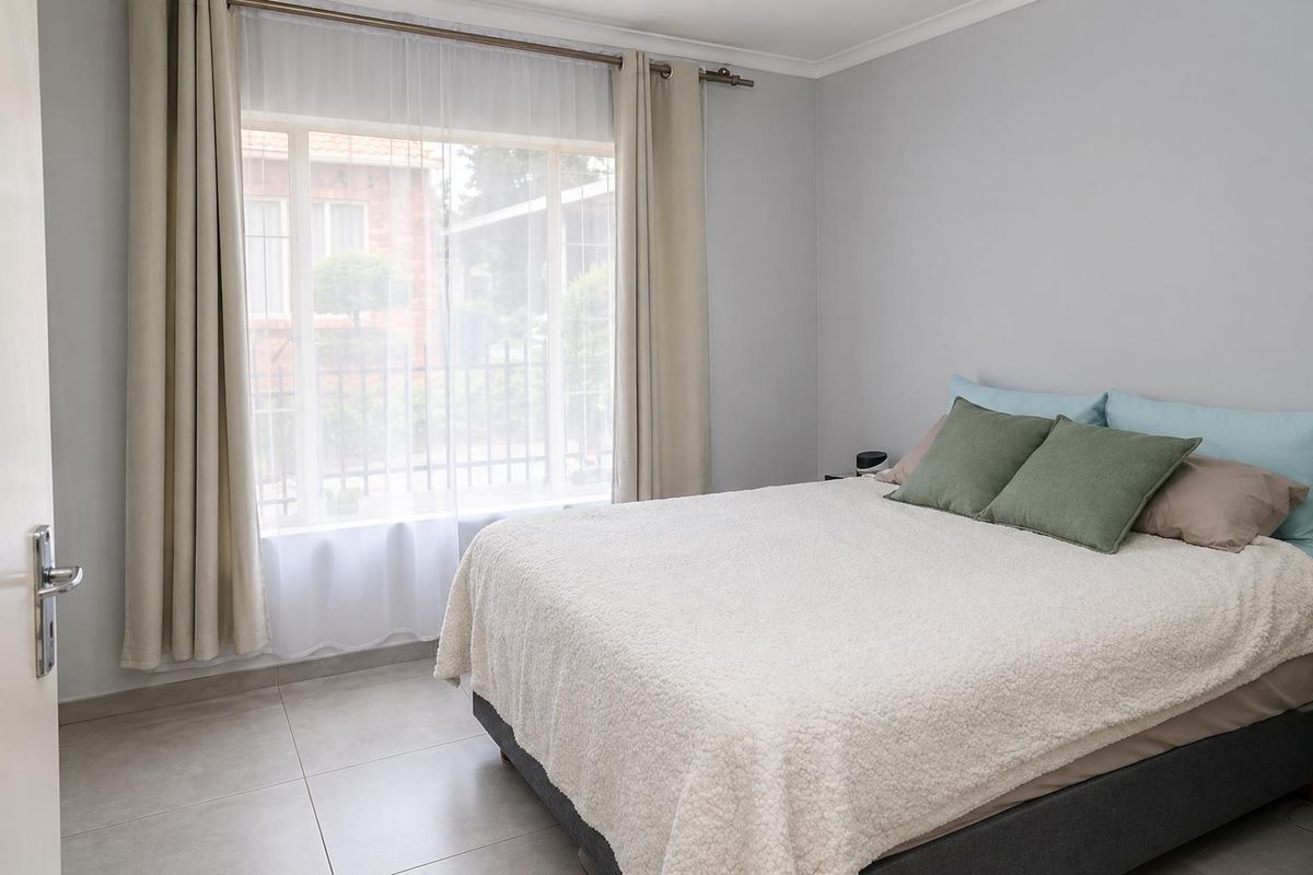 A well-maintained bedroom featuring neutral tiled flooring and a large window that allows for natural light.