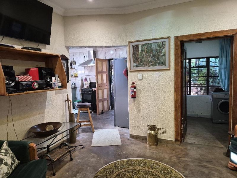 A living area featuring textured walls and concrete flooring, with an open transition to the kitchen and a secondary utility room visible.
