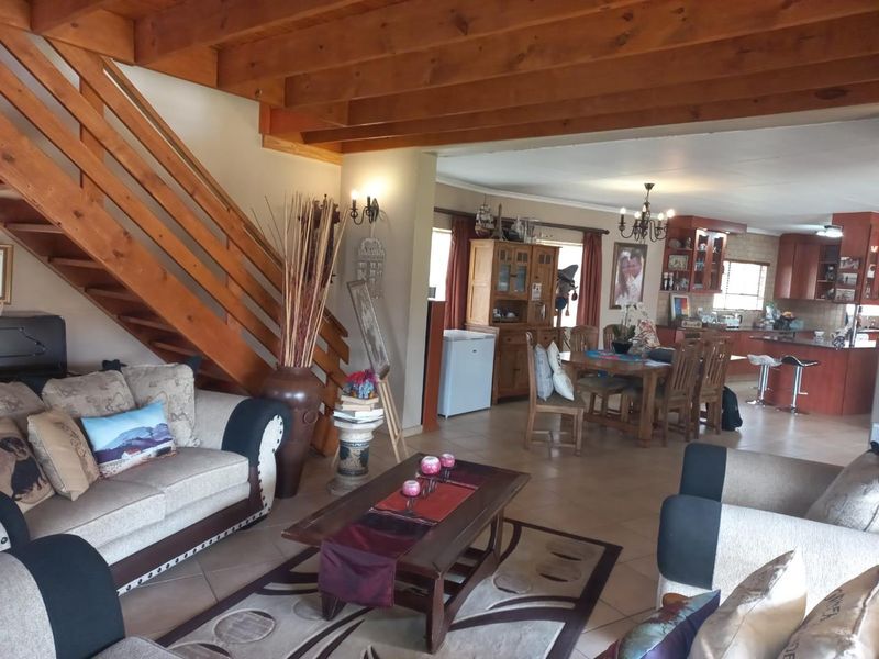 Spacious open-plan living and dining area featuring exposed timber ceiling beams, a wooden staircase, and an integrated kitchen with cabinetry and island.