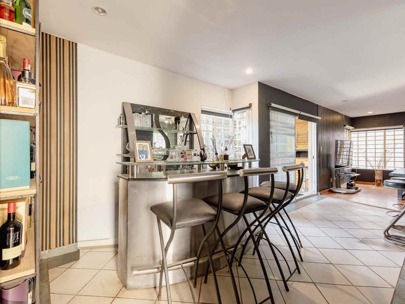 A dedicated bar area featuring a built-in counter, tiled flooring, and direct access to the outdoor patio through sliding glass doors.
