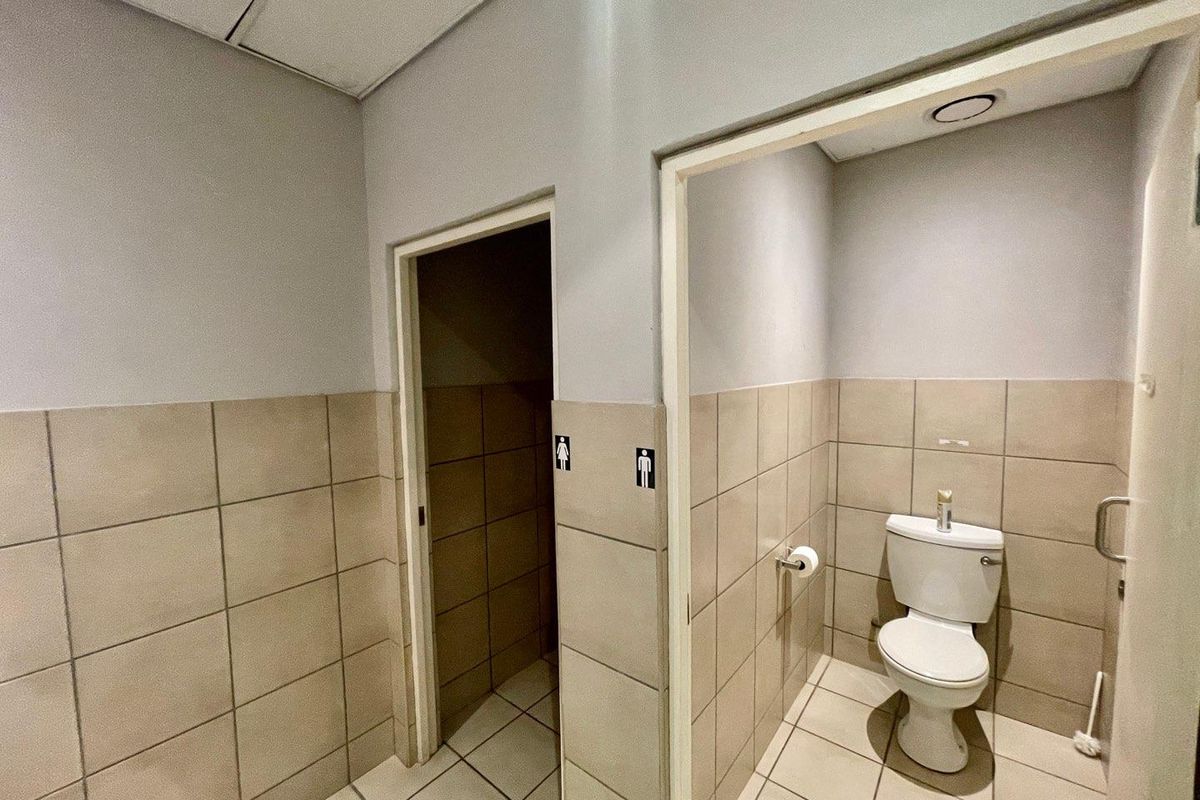 Functional commercial restroom facility featuring tiled walls and floors with separate cubicle access.