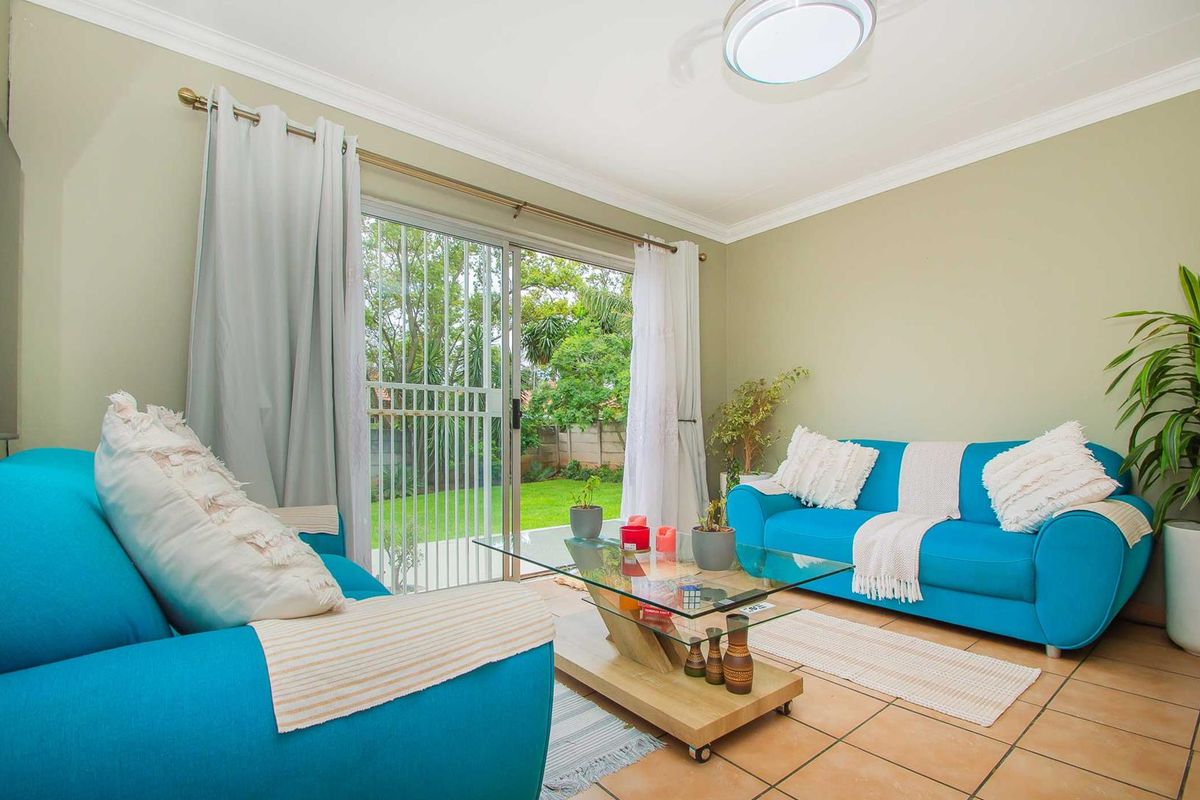A bright living room featuring tiled flooring, crown molding, and large sliding glass doors that provide direct access to the rear garden.