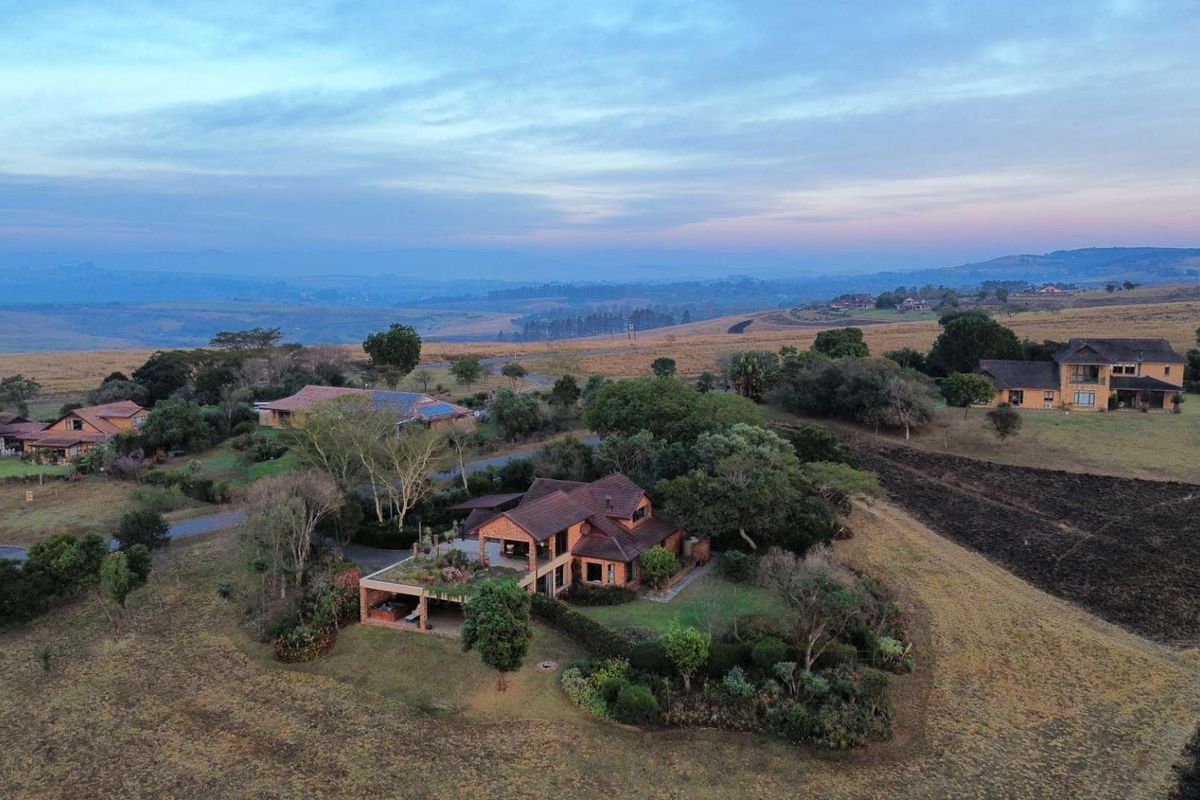 Aerial view of a residential property featuring a tiled roof, covered patio, and established garden set within a scenic rural landscape.