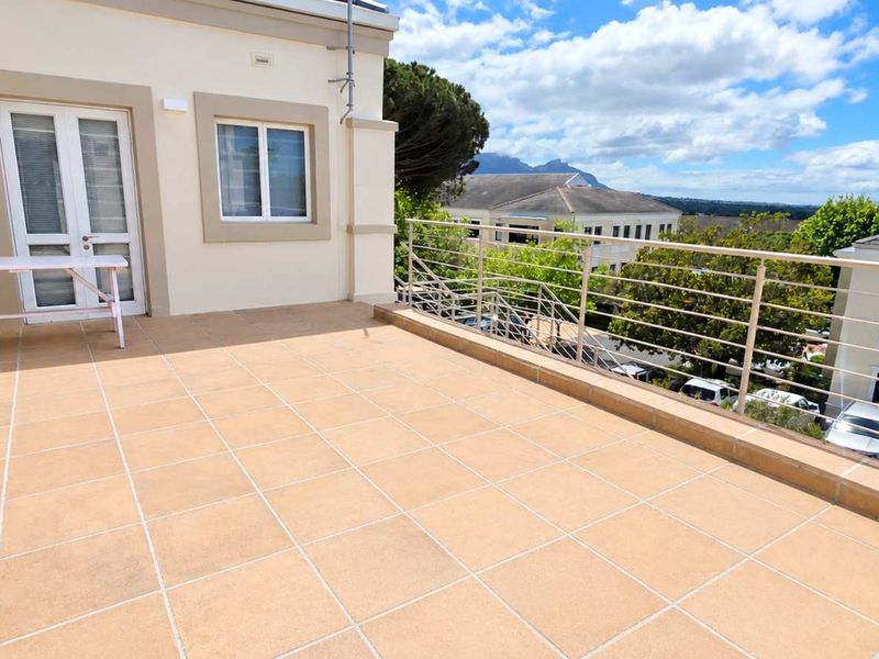 Spacious outdoor balcony featuring tiled flooring, a secure metal balustrade, and direct access to the office interior, offering pleasant views of the surrounding area.