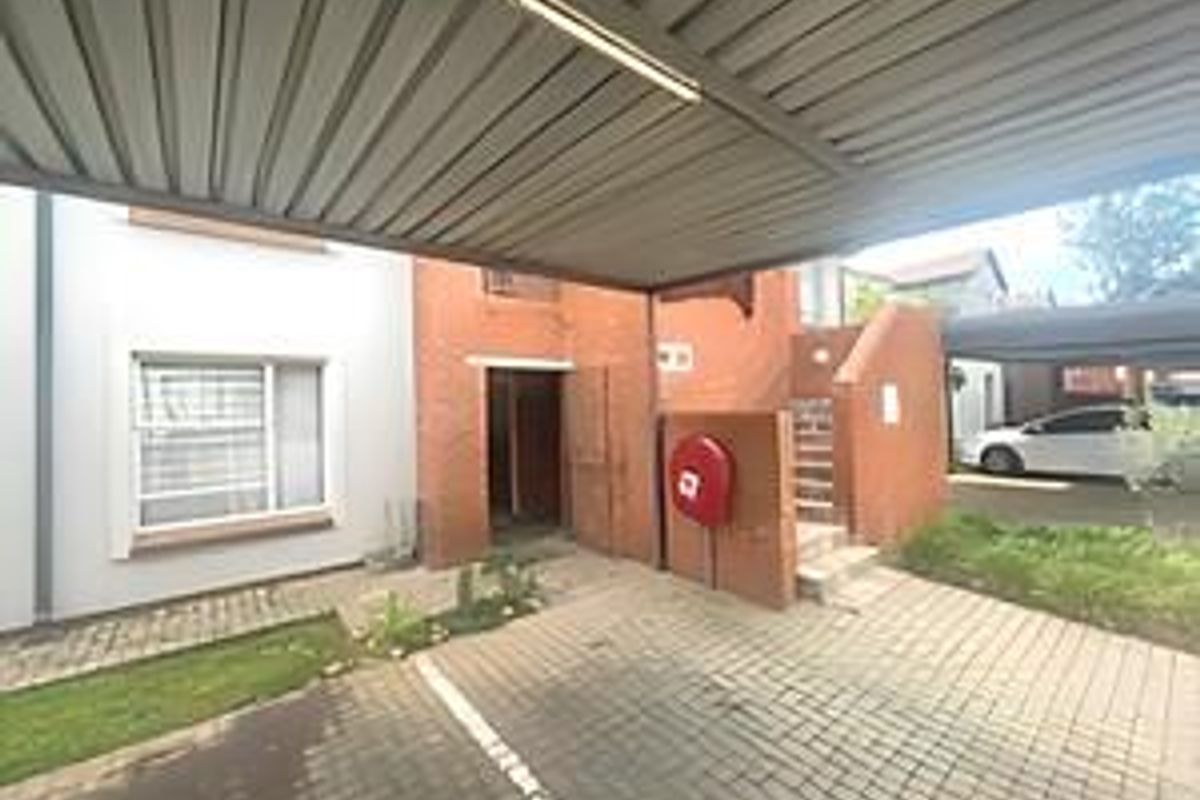 Front exterior view of the cluster property featuring a covered carport, paved driveway, and brick facade with an external fire hose reel.