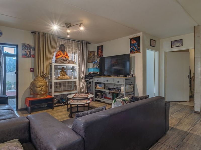 A living room featuring tiled flooring, a ceiling light fixture, and a sliding glass door providing access to the exterior.
