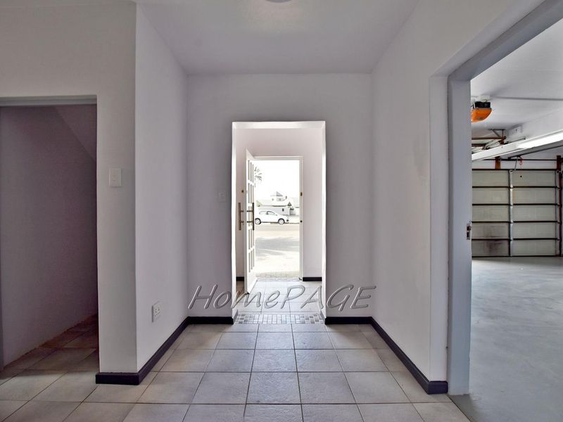 A bright, tiled entrance hall providing direct access to the garage and main living areas, featuring neutral finishes and a clean, open layout.