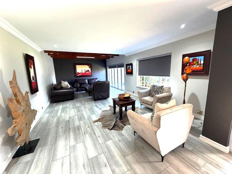 Spacious living room featuring wood-look tile flooring, exposed timber ceiling beams, and large sliding glass doors providing ample natural light.