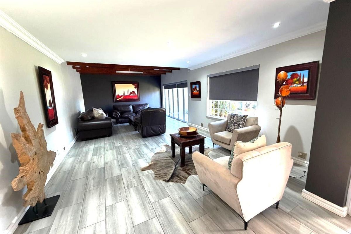 Spacious living room featuring wood-look tile flooring, exposed timber ceiling beams, and large sliding glass doors providing ample natural light.