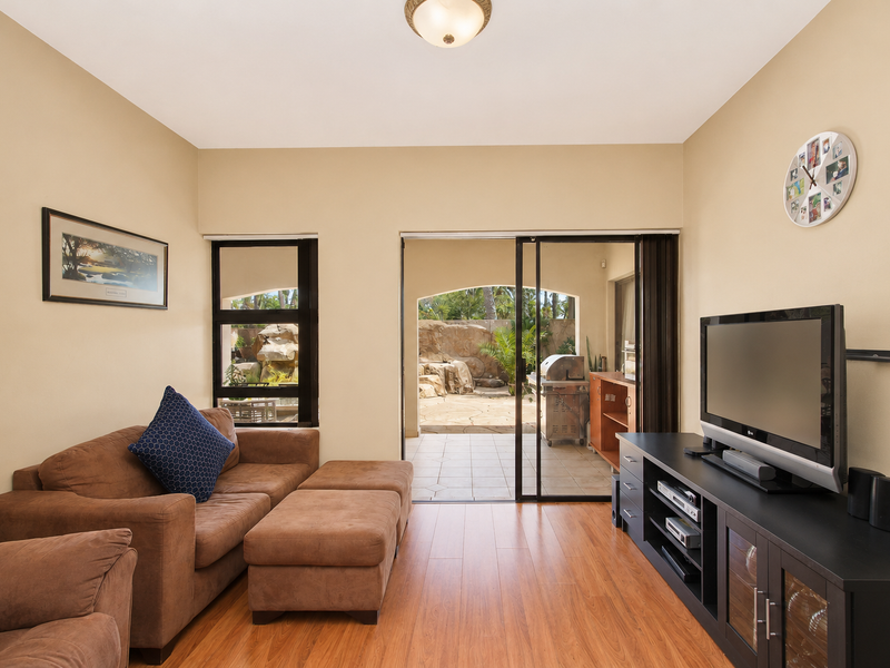 A comfortable living room featuring laminate flooring and large sliding glass doors that provide direct access to an outdoor patio area.