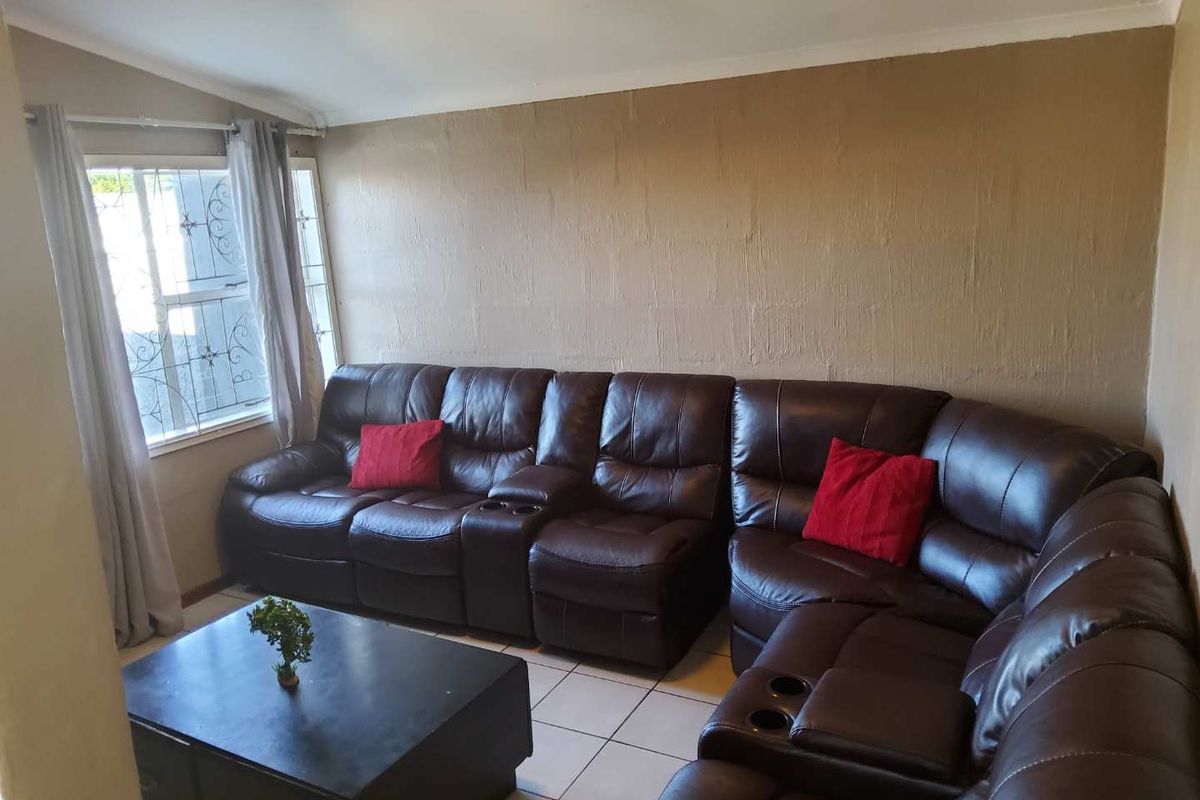 A living room featuring tiled flooring, a window with security bars, and a neutral wall finish.