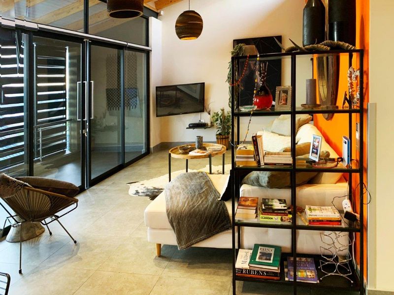 Modern living room featuring exposed timber ceiling beams, large sliding glass doors providing natural light, and sleek tiled flooring.
