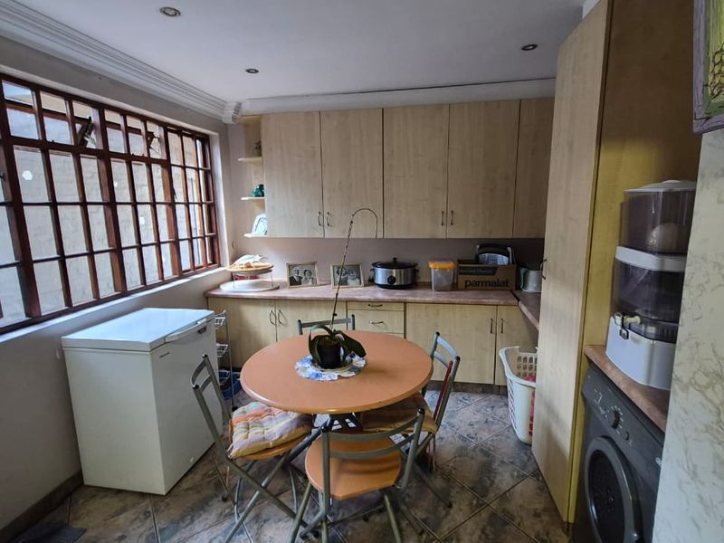 A functional kitchen featuring light wood-tone cabinetry, tiled flooring, and a large timber-framed window providing natural light.