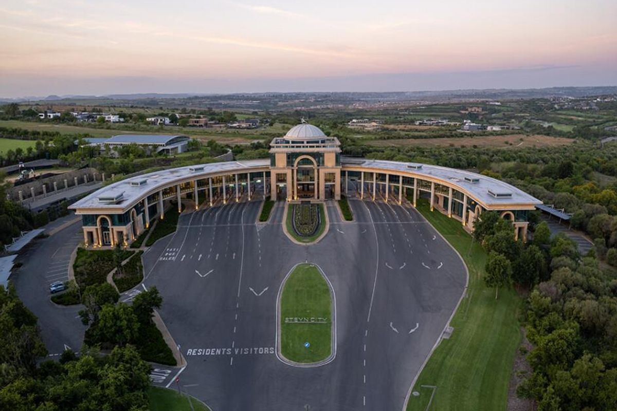 Aerial view of the grand entrance and clubhouse facility at Steyn City, featuring extensive paved driveway, landscaped gardens, and architectural dome structure.