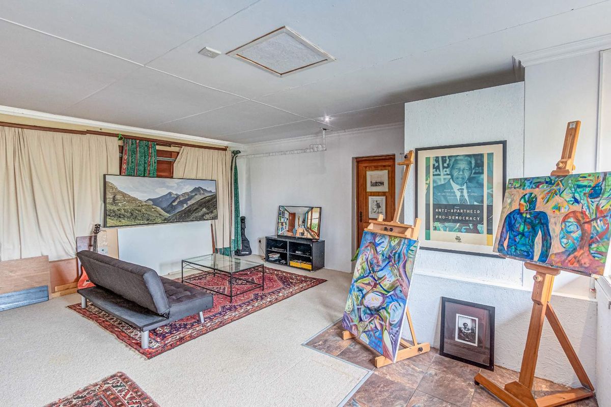A spacious living area featuring a mix of carpet and tiled flooring, with a prominent textured feature wall and exposed conduit detailing.