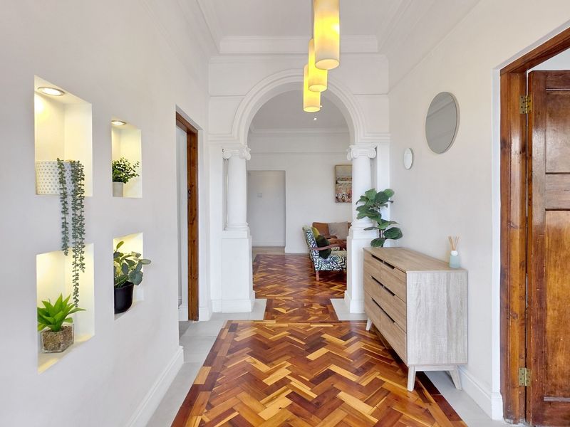 Elegant hallway featuring classic herringbone parquet flooring, a grand arched entryway with decorative columns, and built-in recessed wall niches with integrated lighting.