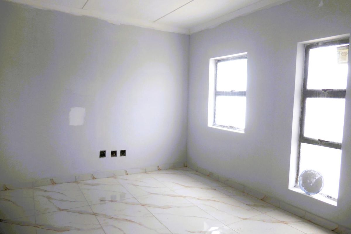 An empty bedroom featuring modern marble-look tiled flooring, aluminium window frames, and neutral wall finishes, ready for personalization.