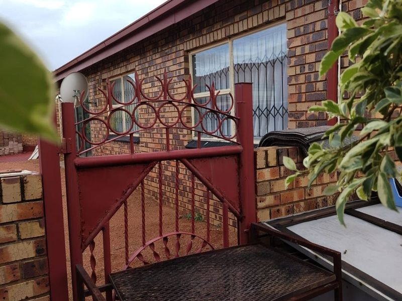 A view of the rear exterior featuring face brick walls, security gates, and window security bars.