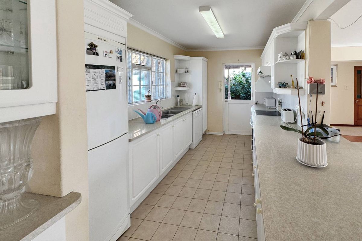 A functional kitchen featuring white cabinetry, laminate countertops, ceramic tile flooring, and direct access to the rear exterior.
