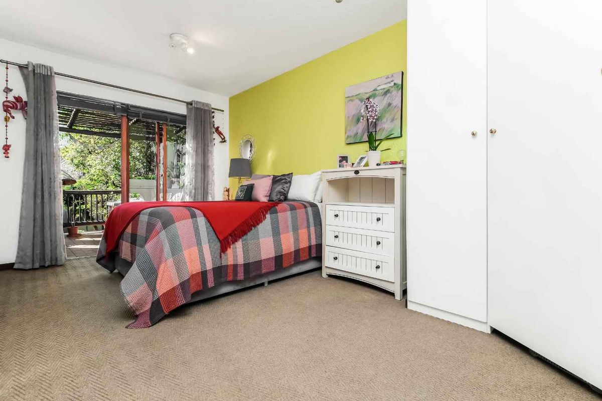 A bedroom featuring built-in cupboards, carpeted flooring, and sliding glass doors that open onto a private balcony.