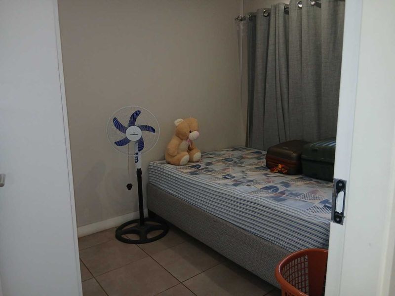 A compact bedroom featuring tiled flooring and neutral wall finishes, offering a functional space for a single bed.