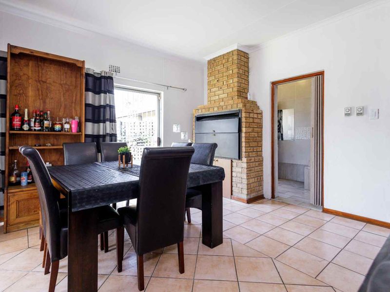 Dining area featuring ceramic floor tiles and a prominent built-in brick fireplace, with direct access to an adjacent room via a folding door.