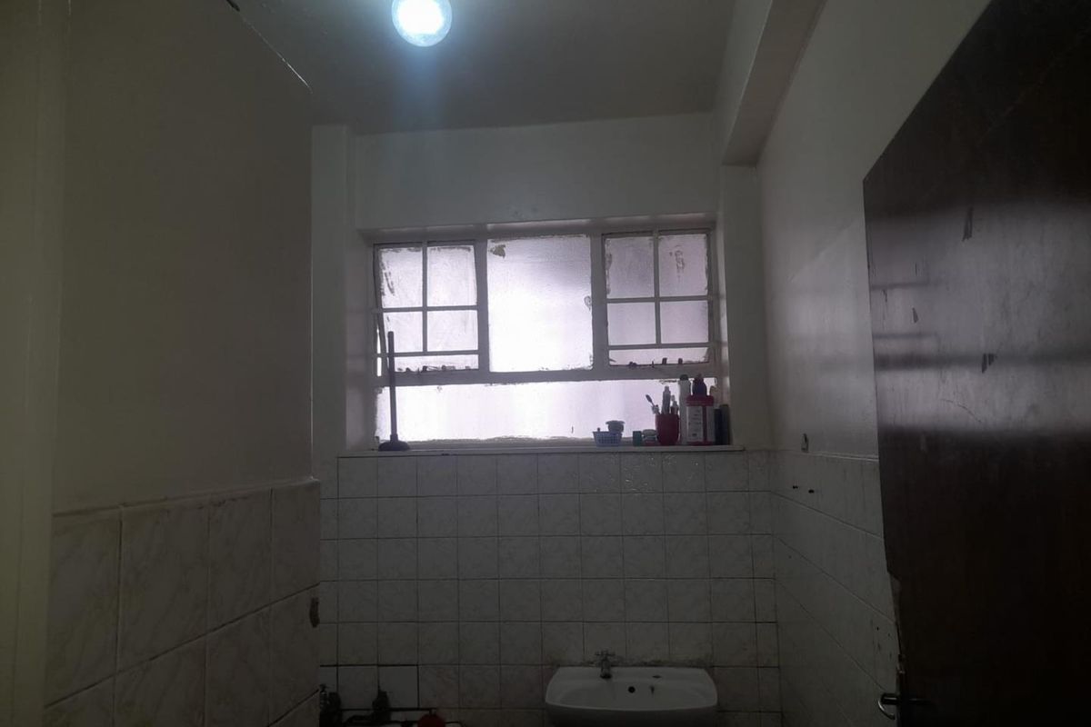 A dated bathroom featuring a pedestal sink, bathtub, and tiled walls, requiring cosmetic updates to improve its overall condition and appeal.