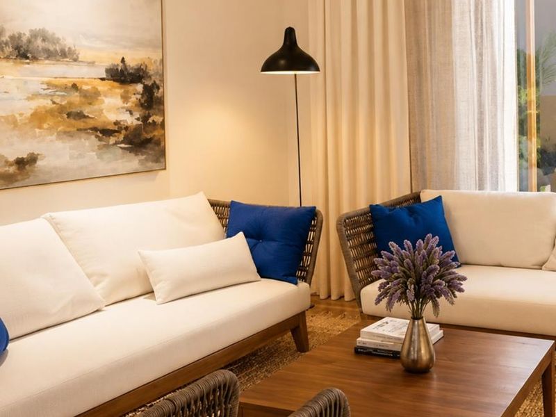 A well-appointed living room featuring neutral tones, floor-to-ceiling curtains, and direct access to an outdoor area.